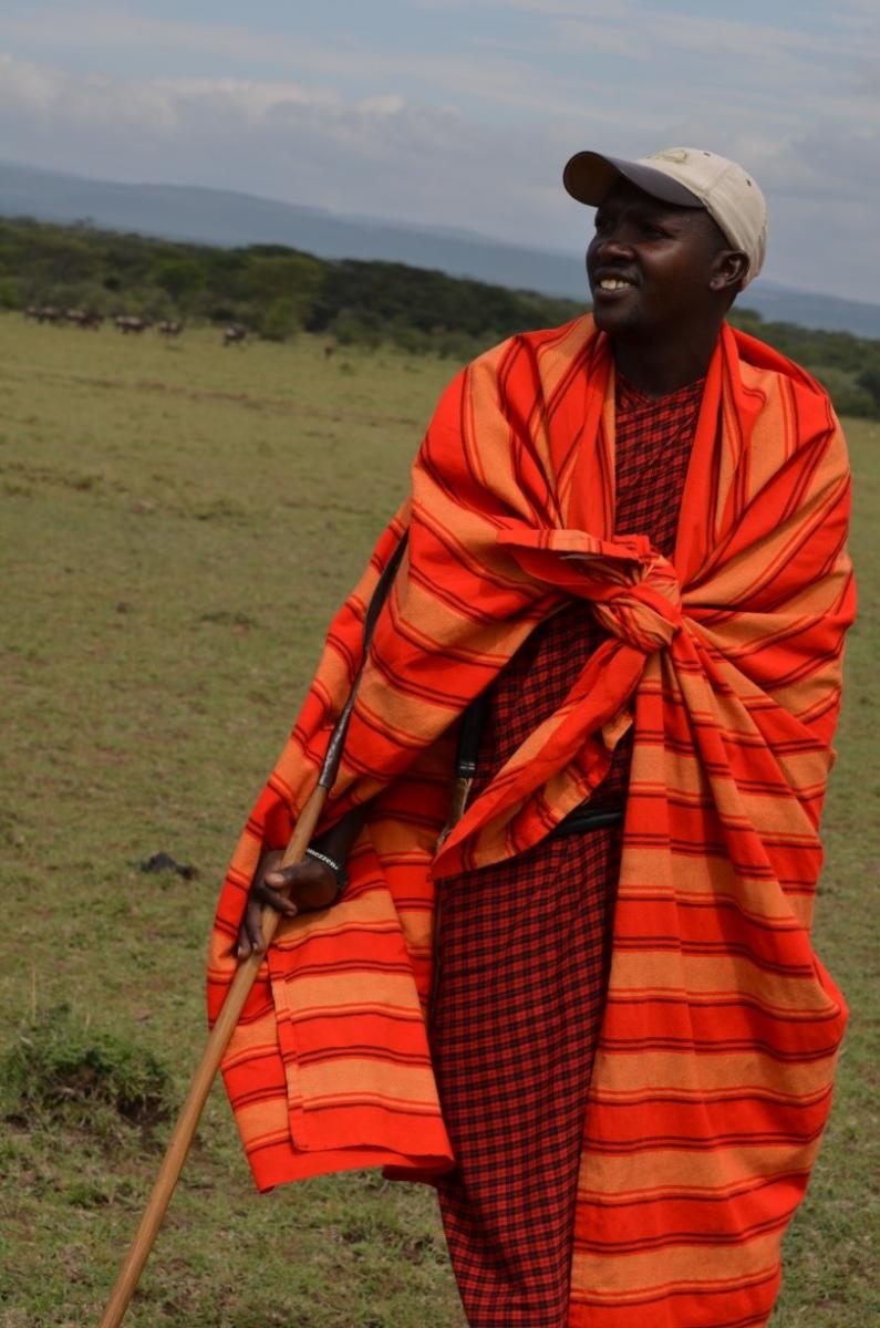 A man with a walking stick in bright cultural garb