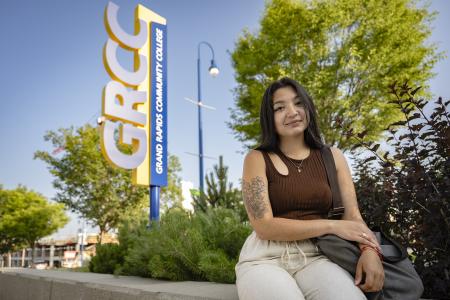 Student sitting in front of a GRCC sign
