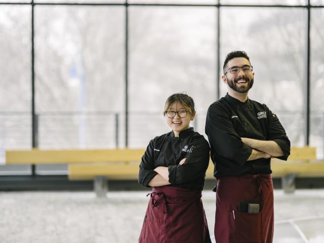Two student chefs stand with crossed arms