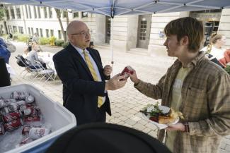 Dr. Lepper hands a student a can of Dr. Pepper.