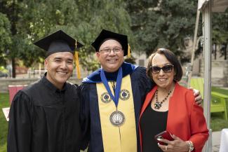 Dr. Lepper, wearing academic regalia, poses with two other people. 