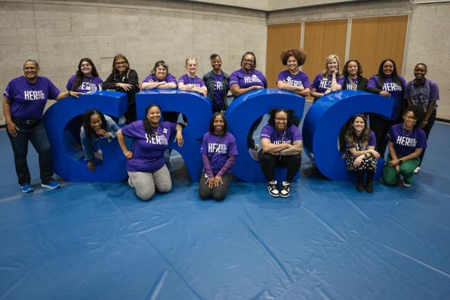 A group of girls grouped around big blue GRCC letters.