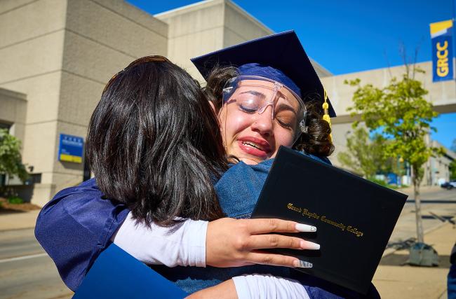 A student graduating in 2021 hugs a family member.