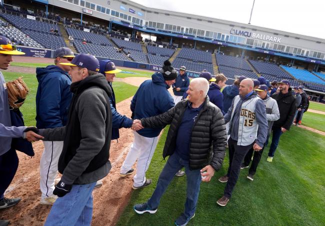 Players from both eras greeting each other on the field at LMCU Ballpark.