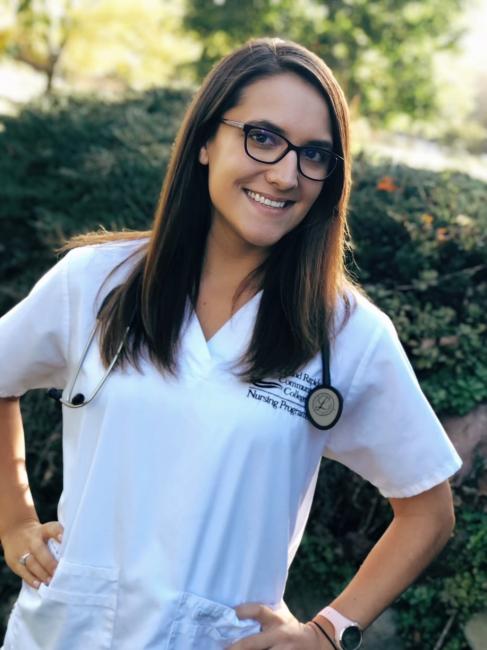 GRCC alumna Nicole Richardson poses outside in her white nursing uniform.