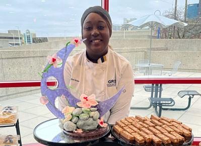 Culinary student Kat DeVries standing behind some of her pastries.