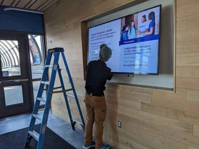 A technician installs a large digital display screen on GRCC's Main Campus.