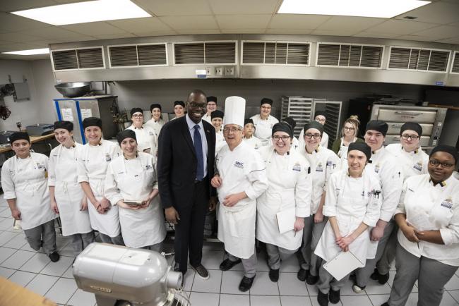 Lieutenatn Governor Gilchrist surrounded by students in the Secchia Institute for Culinary Arts bakery classroom.