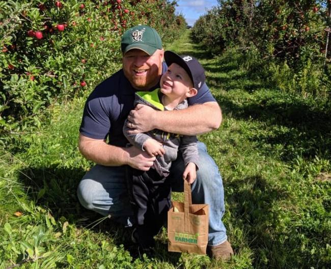 Saniel Schoonmaker with a child in an orchard.
