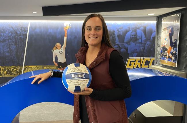 Kaitlyn Bergman holding a volleyball signed by the championship team.