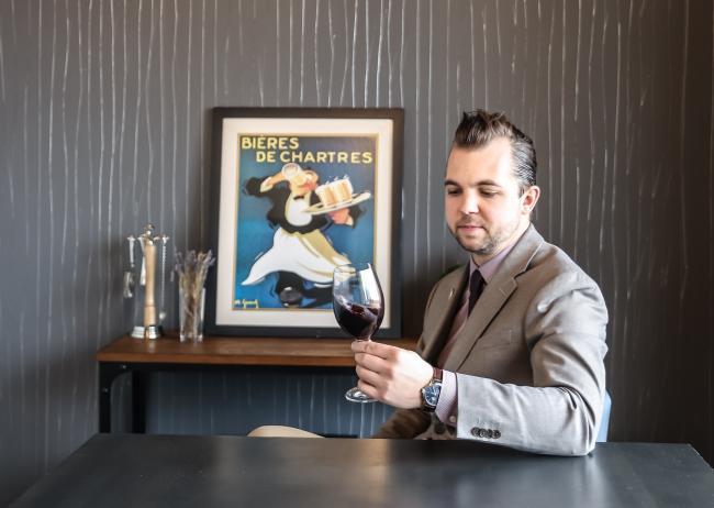 Portrait if Tristan Walczewski with a class of wine.
