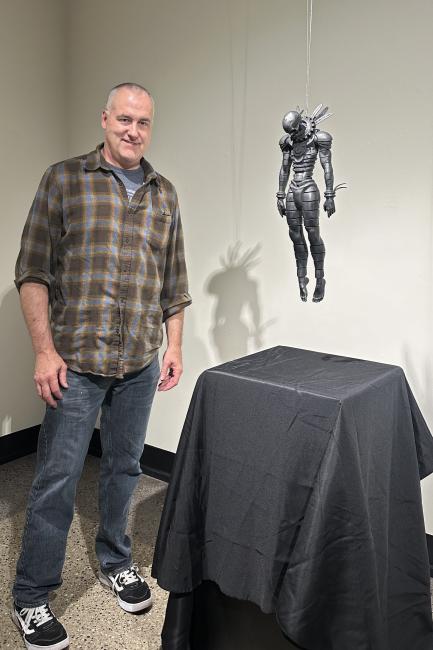 Matthew Schenk poses with his sculpture