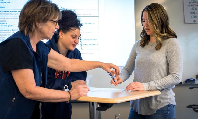 A group of GRCC students demonstrates how occupational therapists work with one participant being shown how to hold a pen.