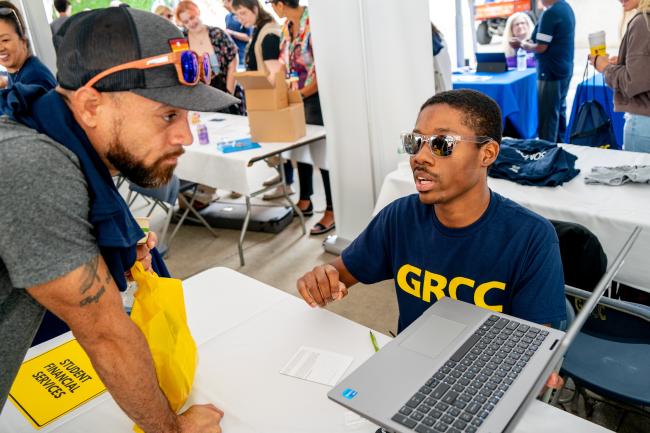 A GRCC staff member working with a student at Raider Rally.