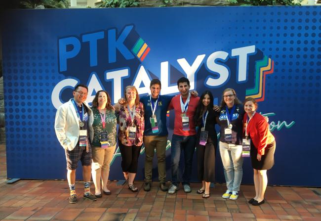 Members of Alpha Upsilon Kappa stand in front of a sign that says "PTK Catalyst."