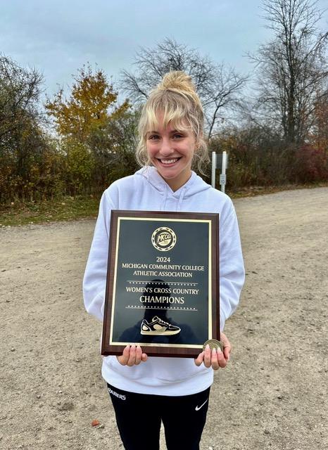 GRCC athlete Mariana Zaragoza holds here cross country champions plaque.