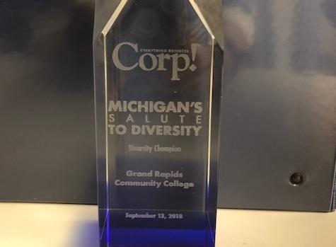 Etched on the glass award, it says: "Corp.! Michigan's Salute to Diversity. Diversity Champion. Grand Rapids Community College. September 13, 2018."