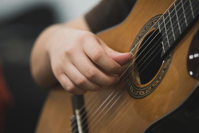 A closeup of hands playing a guitar.