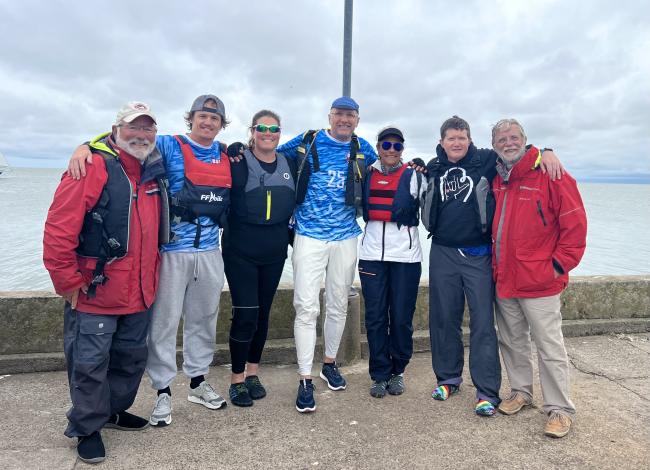 GRCC faculty member Rowan O'Dougherty poses with a group of other sailors near the water.