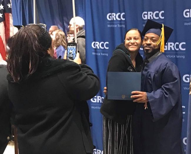 A woman takes a photo of a Job Training graduate and a young woman.