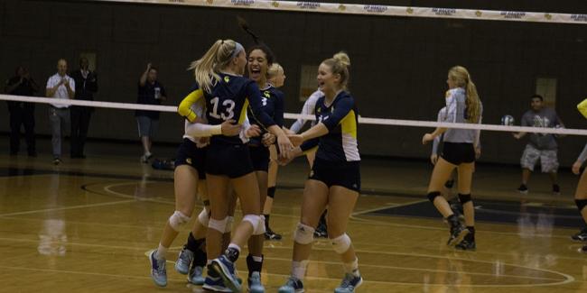 Members of the volleyball team hug in front of the net.
