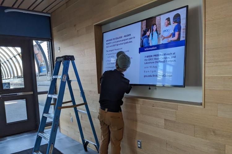 A technician installs a large digital display screen on GRCC's Main Campus.