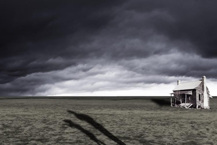 A piece by Andrew Caldwell featuring a house in a field under a dark sky.