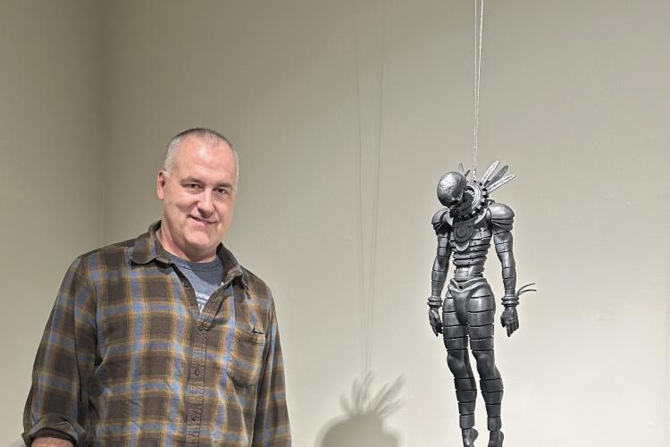 Matthew Schenk poses with his sculpture