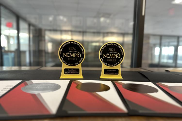 Seven awards placed on a table, representing the recognition GRCC's Marketing and Communications team received from the National Council for Marketing and Public Relations.