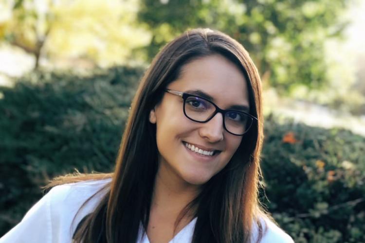 GRCC alumna Nicole Richardson poses outside in her white nursing uniform.