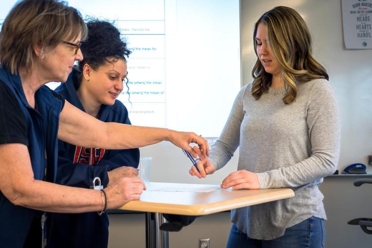 A group of GRCC students demonstrates how occupational therapists work with one participant being shown how to hold a pen.