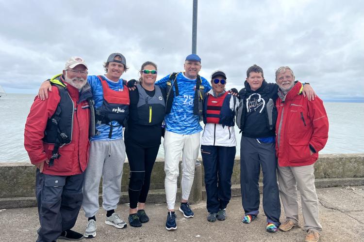 GRCC faculty member Rowan O'Dougherty poses with a group of other sailors near the water.