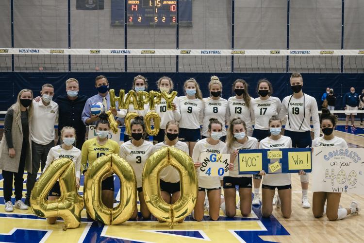 Coach will and players celebrating the 400th win with balloons.