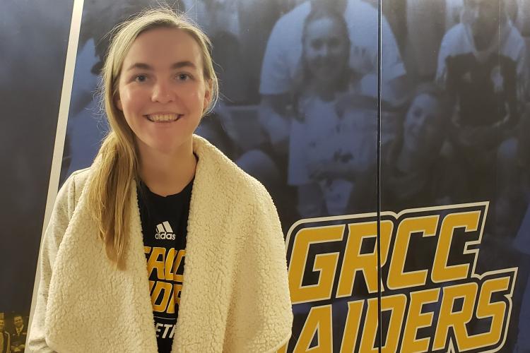 Amanda Glaza standing in front of a GRCC Raiders Logo.