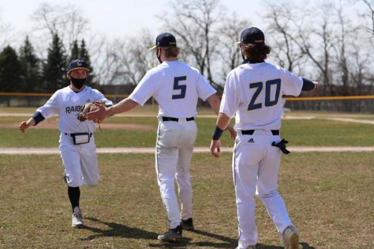 GRCC baseball players celebrating after scoring a run.