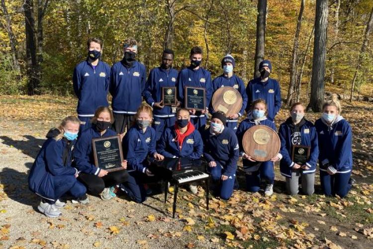 Team photo of cross country teams holding their championship plaques