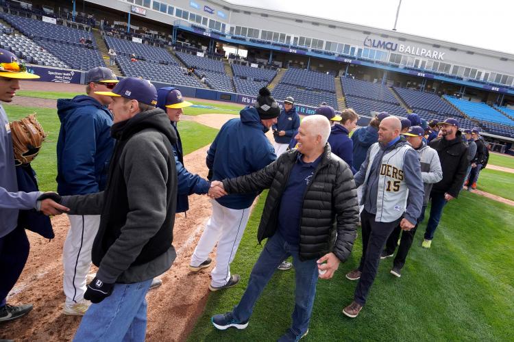 Players from both eras greeting each other on the field at LMCU Ballpark.