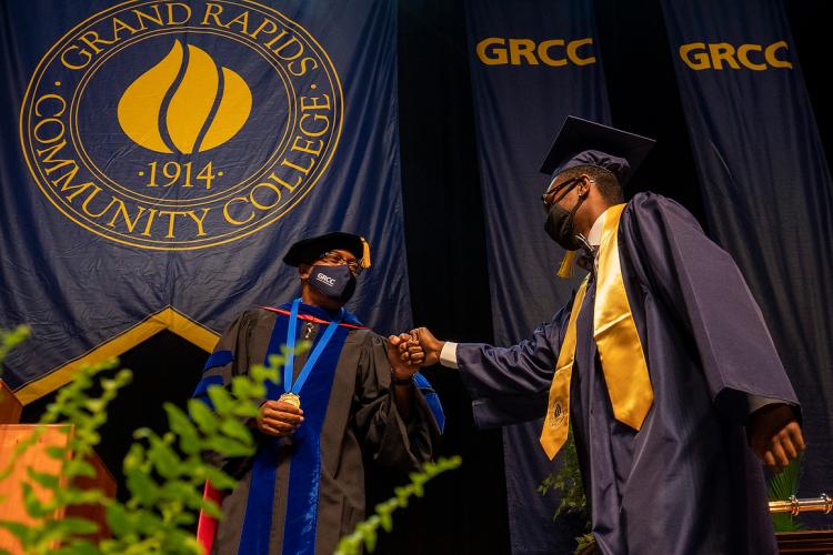 GRCC President Bill Pink fist-bumps a graduate.