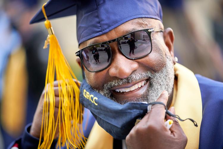 Photo of a student at commencement removing his mask.