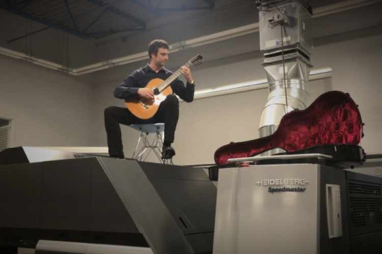 GRCC guitar instructor Jonathan Marshall performing atop a printing machine.