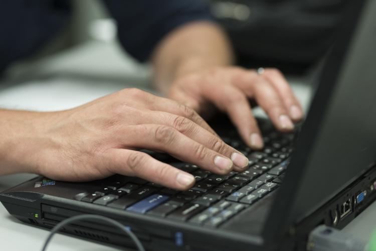 Hands of a student working on a laptop.