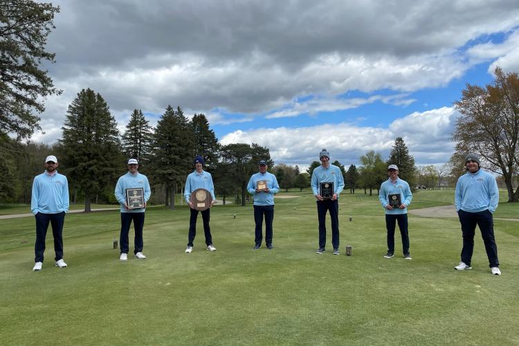 Golf team members posing with their trophies.