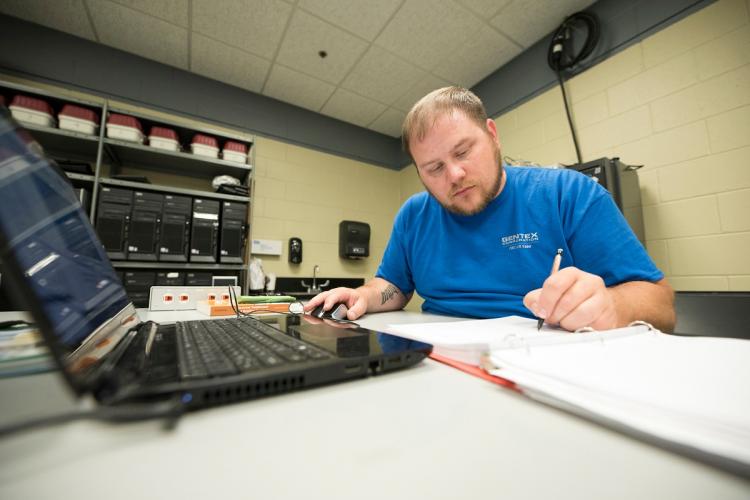 GRCC student working on a laptop in a business setting.