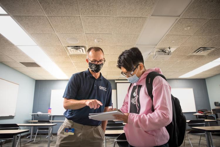 GRCC professor talking with a student, both wearing face coverings.