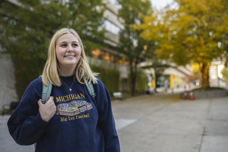 A student in a University of Michigan sweatshirt on Olivarez Plaza.