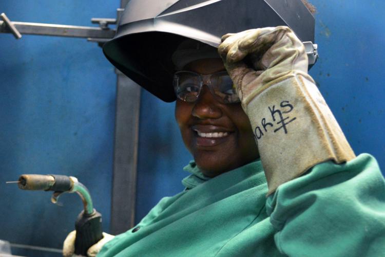 Welding student and Metallica Scholar Uniqua Sparks smiles as she lifts up her welding helmet.