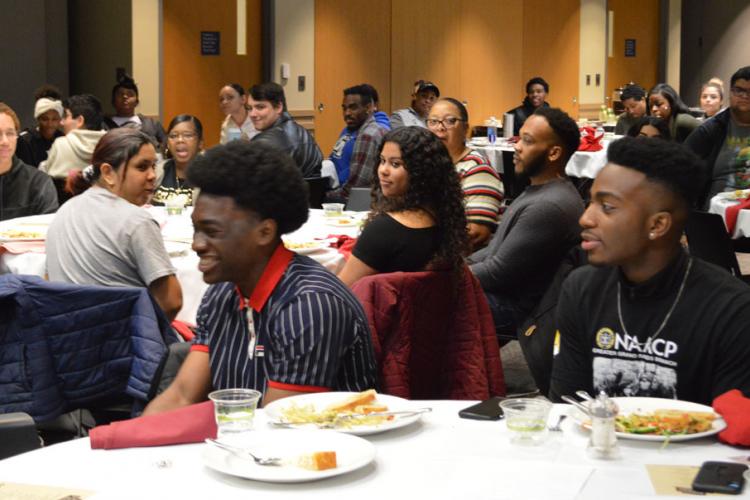 Students sitting a table reacting to a speaker.