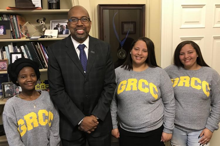 GRCC President Pill Pink posing in his office with the valedictorian from Central Innovation High and the valedictorian and salutatorian from Ottawa Hills High.