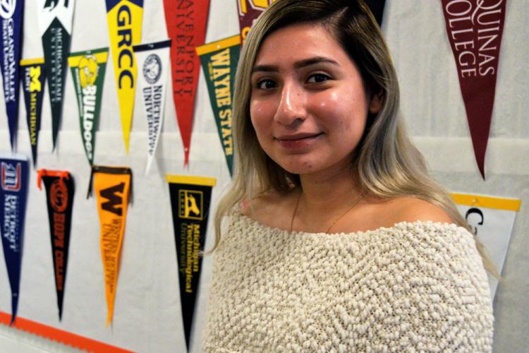 UPrep student Karla Lopez standing in front of college pennants.