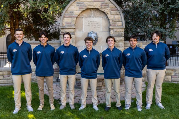 Golf team posing with iconic lion fountain.